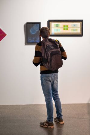 St. Petersburg, Russia. February 15, 2020. A young man with a backpack, a tourist, examines works at the exhibition of contemporary art in the museum.のeditorial素材