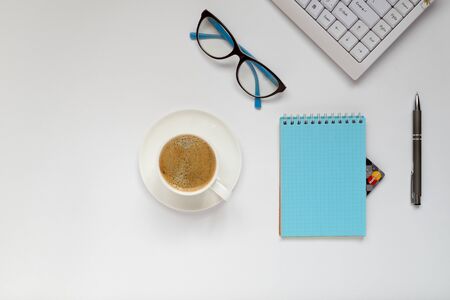A keyboard, a cup of coffee, a pen, glasses and a notebook from which you can see the credit card corner. Shopping online, quarantine concept. Copy Space. Horizontal orientation. View from above.の写真素材