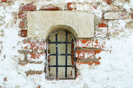 Fragment of an old brick wall with a small window. Horizontal orientation, selective focus