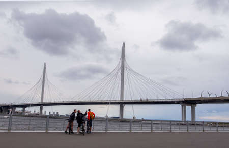 St. Petersburg, Russia. July 04, 2020. View of the Western Expressway Bridge and the Gulf of Finland. Three young men on bicycles take a selfie. Horizontal orientation, selective focus.のeditorial素材