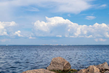 View from the rocky shore to the bay and the city buildings on the opposite bank on a summer day....