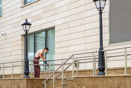 St. Petersburg, Russia. - July 21, 2020. The janitor in the medical mask washes railing. Sanitary treatment. Selective focus.のeditorial素材