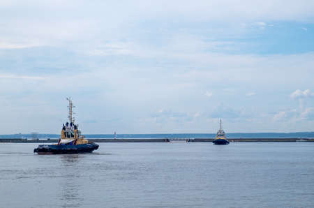 Kronshtadt, Saint Petersburg, Russia - July 20, 2020. Two tugs sail through the harbor of the seaport on a summer day. Horizontal orientation, selective focusのeditorial素材