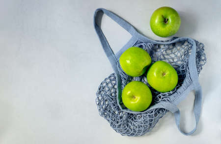 Several green apples are in a string bag. The concept is plastic free, environmental protection, healthy lifestyle. Horizontal orientation, top view, copy space.の写真素材