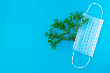 Christmas New Year background with branches of a Christmas tree and a medical mask. Horizontal orientation, selective focus, top view. Copy space.の写真素材
