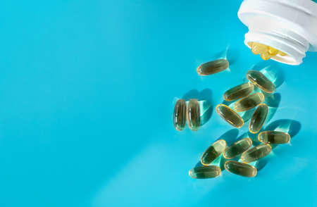 The fish oil capsules are poured out of the bottle. Super food, healthy food concept. Horizontal orientation, selective focus, copy space.の写真素材