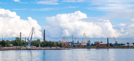 Kronstadt, St. Petersburg: August 29, 2020. View of the commercial port with quays, ships and cranes in loading area across the port water area against beautiful cumulus clouds. Selective focus.のeditorial素材