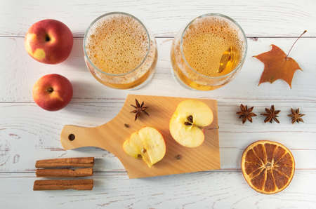 Ripe fresh juicy red apples, spices and glasses with cider on a light wooden surface. Horizontal orientation, selective focus, top view.の写真素材