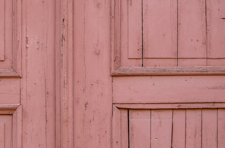 Fragment of an old wooden door painted with pink paint. A background from an old surface with cracked paint. Selective focus.の写真素材