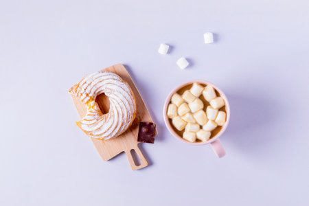 Top view of still life of a bitten cake on a small serving board and a cup of cocoa with...