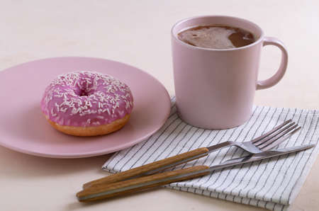 Two sugar-coated donuts lie on a pink ceramic plates. Serving with cutlery, mug of coffee and linen napkin. Selective focus.の写真素材