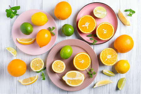 Close-up of whole and cut citrus fruits on pink ceramic plates on a painted natural wood surface. Selective focus.の写真素材