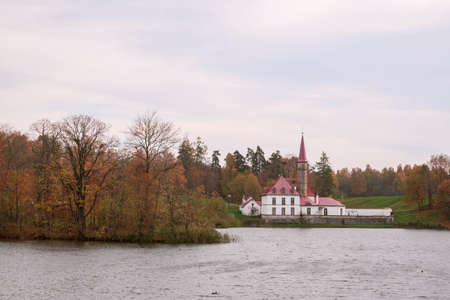 Saint Petersburg, Gatchina, Russia. Nice view of lake and historic Priory castle. Golden autumn, beauty in nature. Selective focus.のeditorial素材