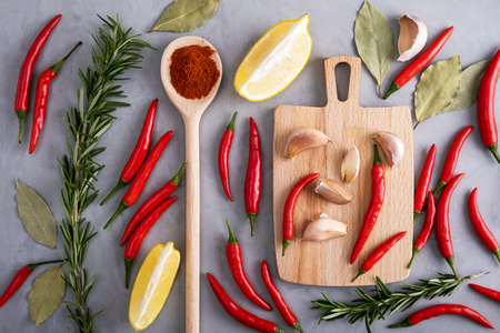 Pods of red hot pepper among other spices on gray surface with plaster texture. Healthy and wholesome food, food preparation. Selective focus. View from above.の写真素材