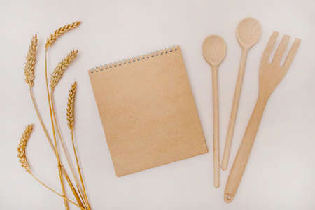 Close up top view mockup template of eco friendly recycled paper notepad, wooden kitchen tools and...