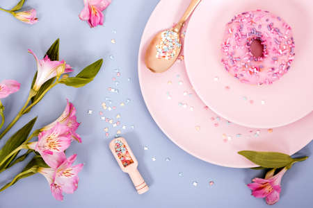 Top view flat lay spring or summer composition in pastel pink and blue colors from plates, donut and...