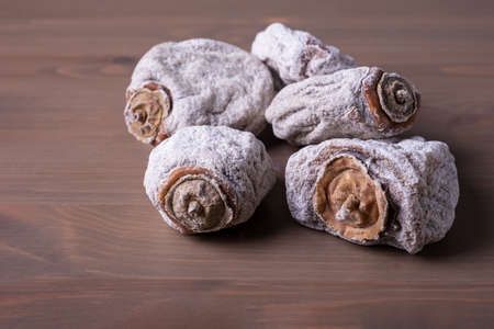 Several dried persimmons on a wooden surface. This is a useful product for diseases of the endocrine...