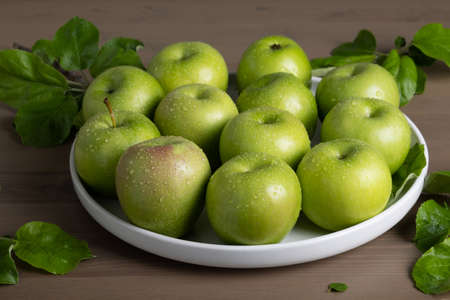 Top view of a composition of fresh ripe green apples and apple tree leaves on a gray background. selective focus.の写真素材
