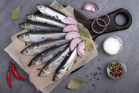 Close-up top view of several pickled herrings with spices on parchment paper on a serving board. selective focus.の写真素材