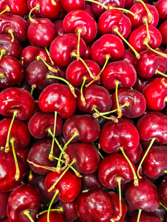 Freshly harvested ripe cherries piled closely together, showing off their vibrant red color and texture.の写真素材