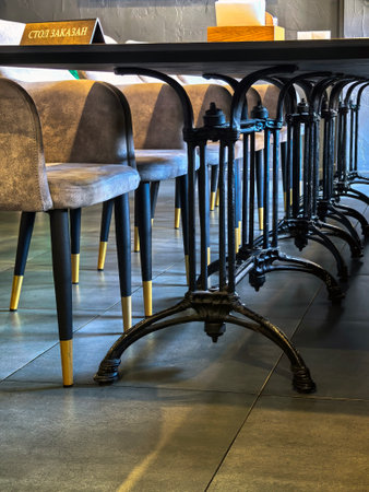 Saint-Petersburg, Russia - 02/08/2025. Elegant dining setting featuring chairs with black and gold legs surrounding a reserved table.の写真素材