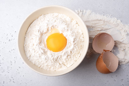 Egg yolk positioned in a flour bowl ready for baking. Captures a close-up view of essential ingredients used in the kitchen to prepare baked goods.の写真素材