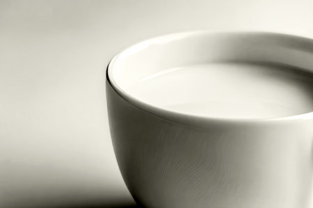 Overhead view of a simple white cup filled with milk, in the shade Cloud Dancer, named color of the year 2026. AI generated.の素材