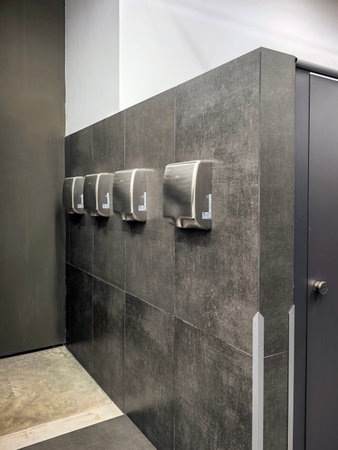 Kronstadt, Saint Petersburg, Russia - January 7, 2026. Stainless steel automatic hand dryers mounted on a tiled public restroom wall, lined up for use. Made on a smartphone.のeditorial素材