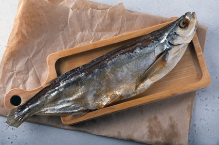 Salted saber carp fish displayed on brown paper presents a rustic culinary scene. The fish's glossy exterior and natural texture offer a traditional look, emphasizing its preserved state.の写真素材