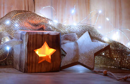 Horizontal Christmas, New Year composition with a wooden candlestick with a star-window, a luminous Christmas garland and a wooden Christmas toy in the form of a star.の写真素材