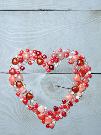 Heart made of pink and red glass beads on a blue wooden table with a place for an inscription....