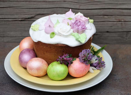 Easter cake decorated with sugar flowers and multi-colored Easter eggs in pastel colors, spring...