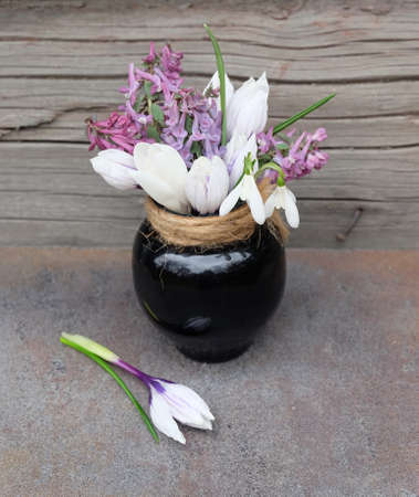 Bouquet of spring flowers (Crocuses, Scilla, Corydalis) in a ceramic small vase, spring festive composition, selective focus, vertical orientation.の写真素材