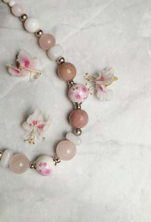 Necklace made of glass, porcelain and rose quartz beads and chestnut flowers, composition with women's jewelry, selective focus, vertical orientation.の写真素材