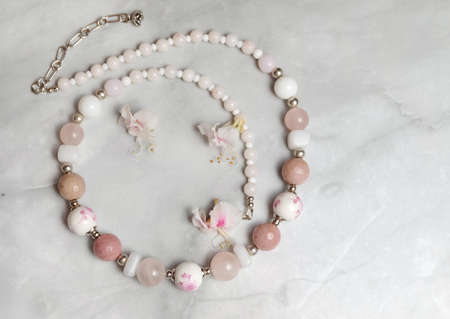 Necklace made of glass, porcelain and rose quartz beads and chestnut flowers, composition with women's jewelry, selective focus, horizontal orientation.の写真素材