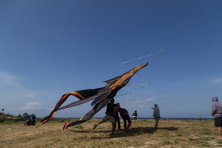 Sanur, Bali, Indonesia - July 19, 2015: A group of people is starting a gigantic kite at Sanur Beach.のeditorial素材