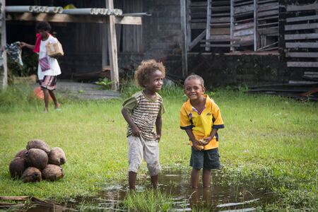 Batuna, Solomon Islands - May 28, 2015: Two boys are playing in a puddle of water at the local market in Batuna village.のeditorial素材