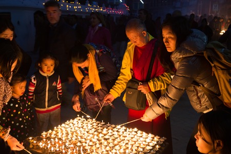 Kathmandu, Nepal - December 06, 2014: Pilgrims at Boudhanath stupa lighting up butter candles for...