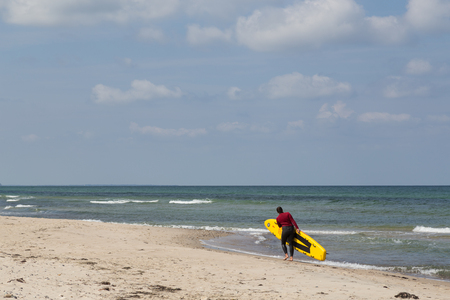 Tisvilde, Denmark - June 20, 2016: A female Lifeguard with her surf board at Tisvilde beach.のeditorial素材