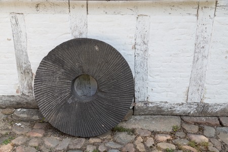 An old millstone standing on a wall.の写真素材