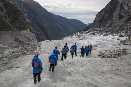 Franz Josef, New Zealand - March 22, 2015: A group of tourists hiking towards a helicopter on Franz Josef Glacier.のeditorial素材