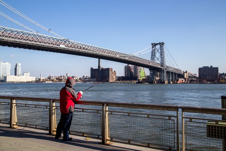 New York, United States of America - November 17, 2016: A man fishing at the Williamsburg Bridge in Manhattan in New York Cityのeditorial素材