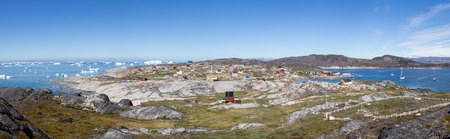 Rodebay, Greenland - July 09, 2018: Colorful wooden houses with icebergs in the background. Rodebay, also known as Oqaatsut is a fishing settlement north of Ilulissat.のeditorial素材