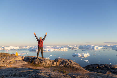 Young man looking at the Ilulissat Icefjord during midnight sun.の写真素材
