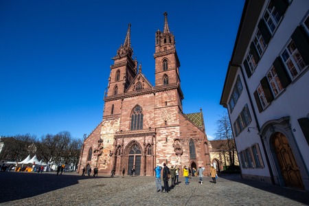 Basel, Switzerland - March 10, 2019: Basel Minster with people in front of it. The Basel Minster is one of the main landmarks and tourist attractions of the Swiss city of Basel.のeditorial素材
