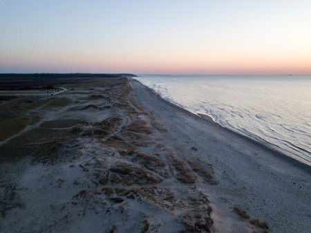 Melby, Denmark - April 18, 2019: Aerial drone view of the coastline beach, sand dunes and forest during sunset.の写真素材