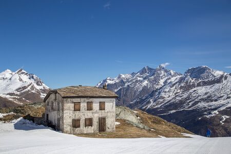 Zermatt, Switzerland - April 13, 2017: A stone hut next to a skiing piste in the snowy Swiss Alps.のeditorial素材
