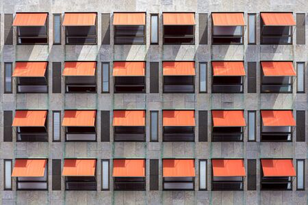 Many red awnings over windows on a office building.の写真素材