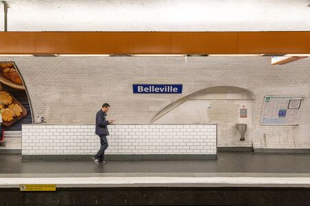 Paris, France - May 12, 2017: A man walking past a sign at Belleville Metro station.のeditorial素材