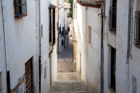 Granada, Spain - May 27, 2019: A narrow alley with white houses in the historic Albaicin district .の写真素材